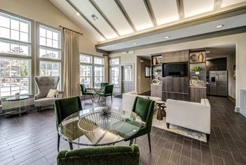 A living room with green chairs and a glass table